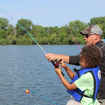 A youth fishing with a police department employee